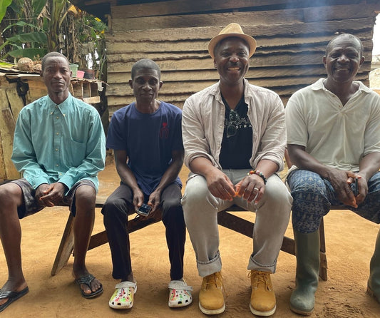 Ebo Nunoo seated on a bench with cocoa farmers in Bawjiase, Ghana