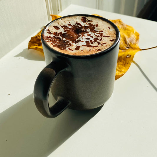 A mug of Xoxoa single-origin hot chocolate topped with chocolate shavings
