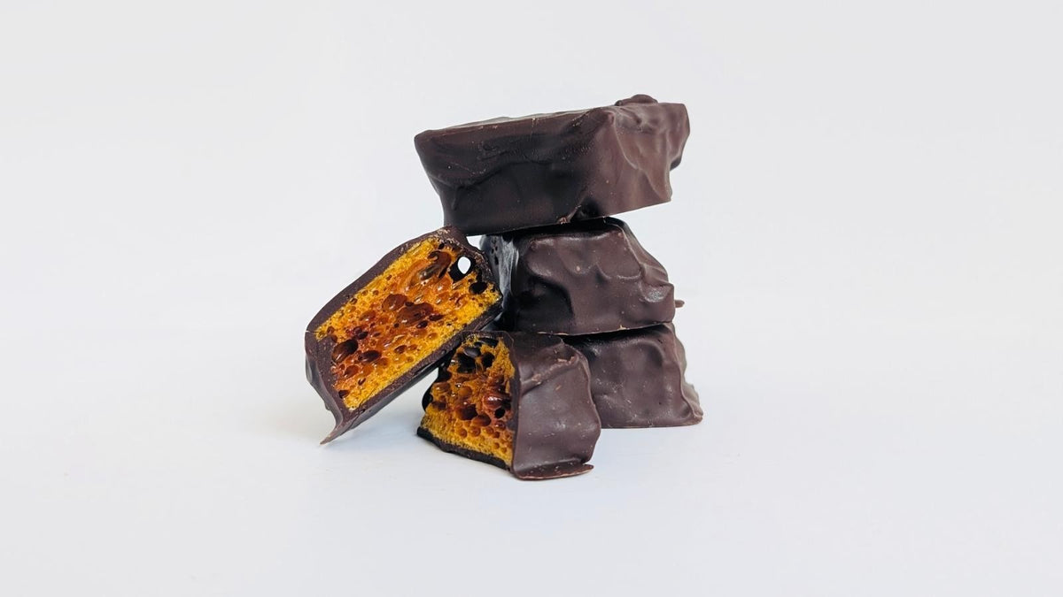 Wild Honey Toffee Crunch pieces stacked, one broken open to show golden honeycomb
